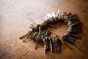 Many old keys on a well used old wooden desk.